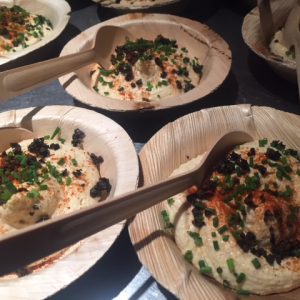 Close up of humus on a small disposable palm tree plate