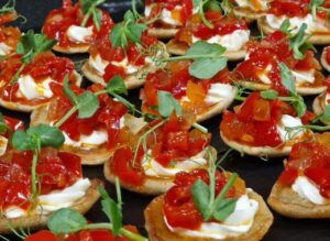 Homemade herbal blini with cream cheese and red bell pepper relish
