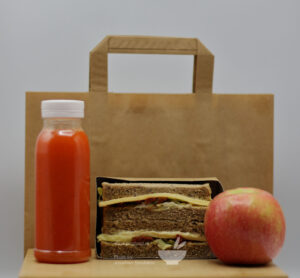 Sample packed lunch with apple, sandwich, juice and candy bar